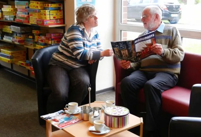 Zwei Personen entspannen, lesen Magazin, trinken Kaffee, Bibliotheks-Loungebereich.