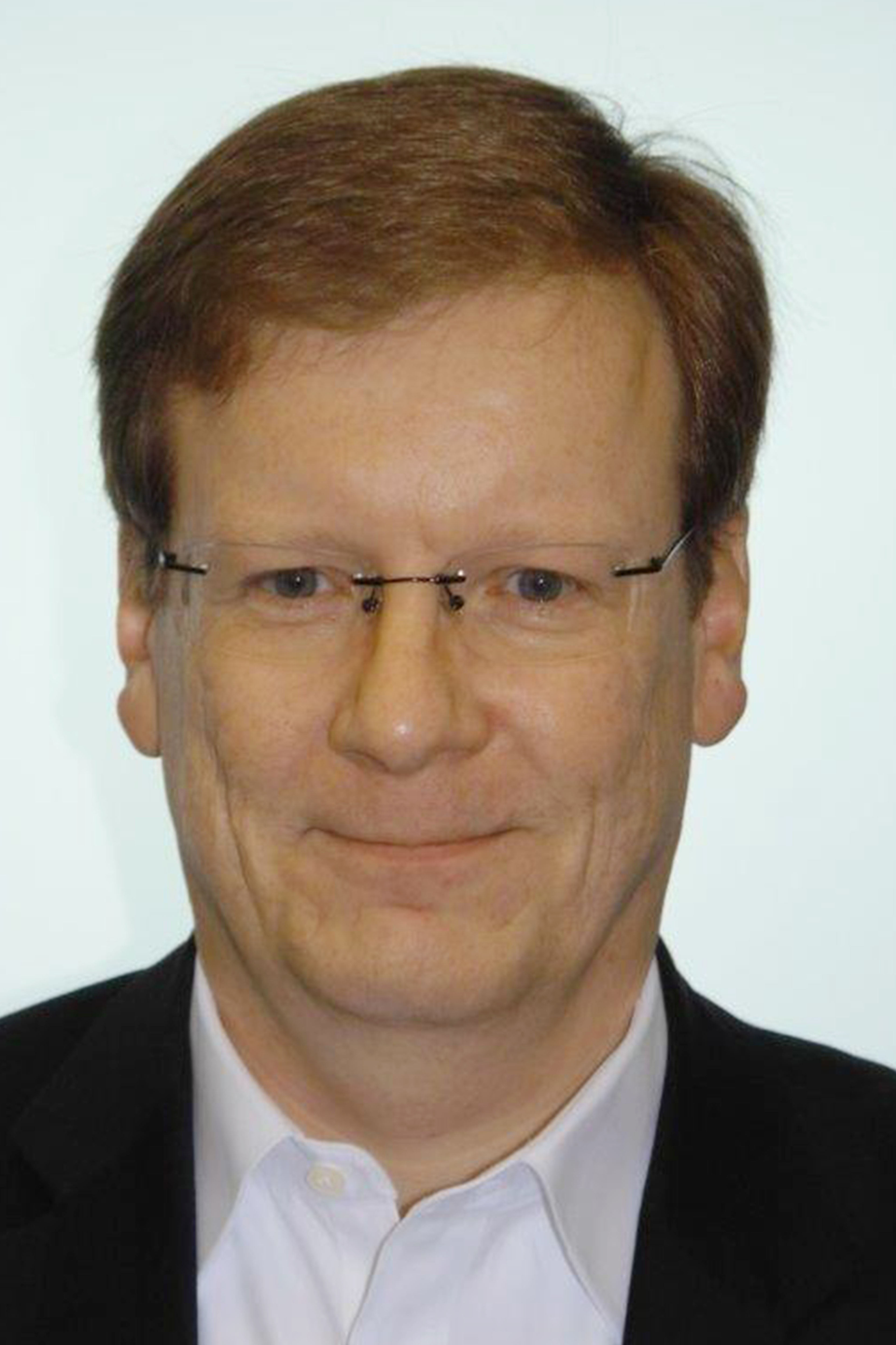 Lächelnder Mann mit kurzen braunen Haaren, Brille und Hemd.