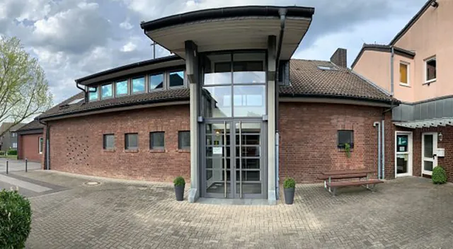 Modernes Backsteingebäude mit großem Glaseingang, möglicherweise eine Klinik.