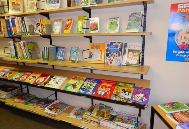 Kinderbücher in Regalen, lebendige Einbände, organisierter Bibliotheksbereich.