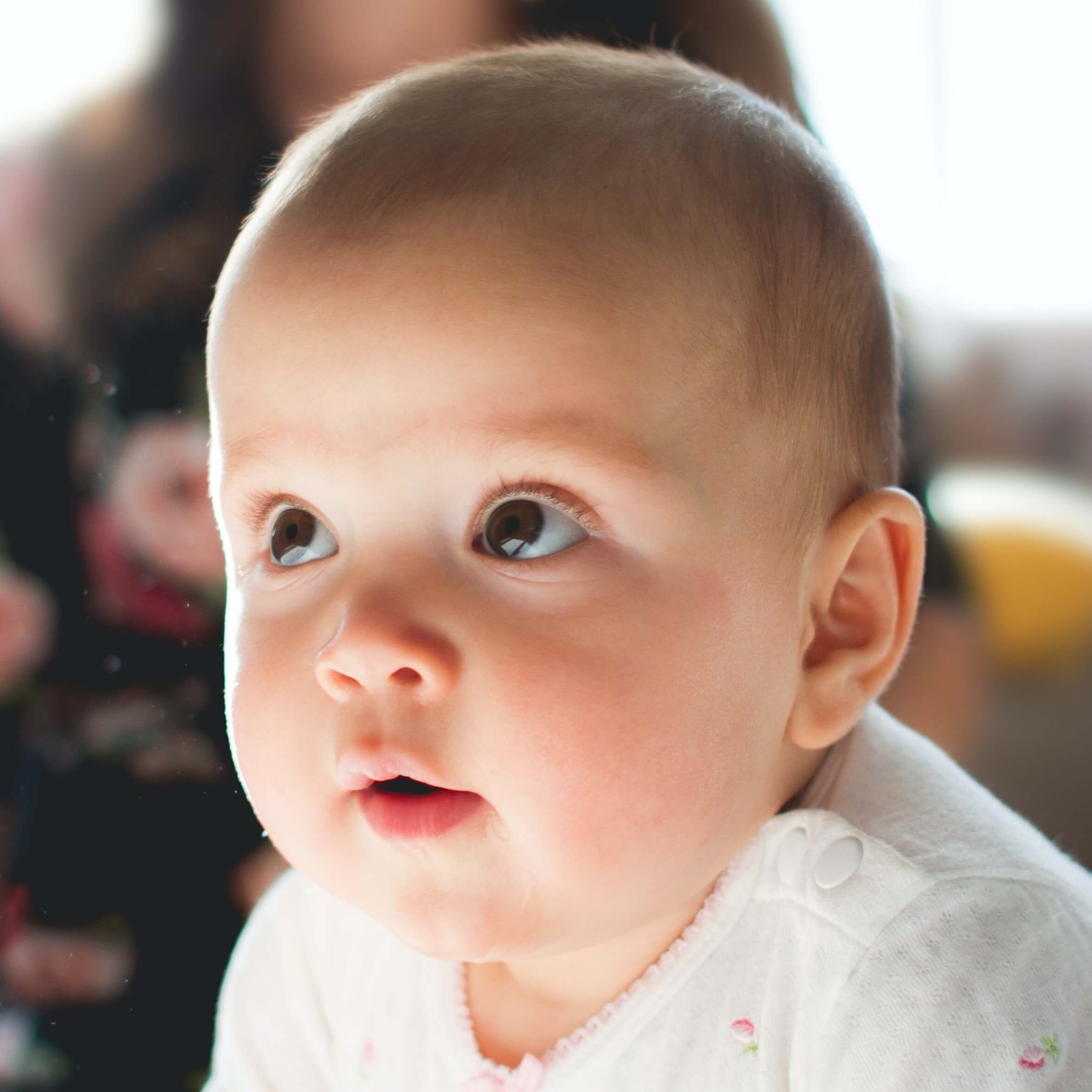 Nahaufnahme eines Babygesichts mit großen, neugierigen, glasigen Augen.