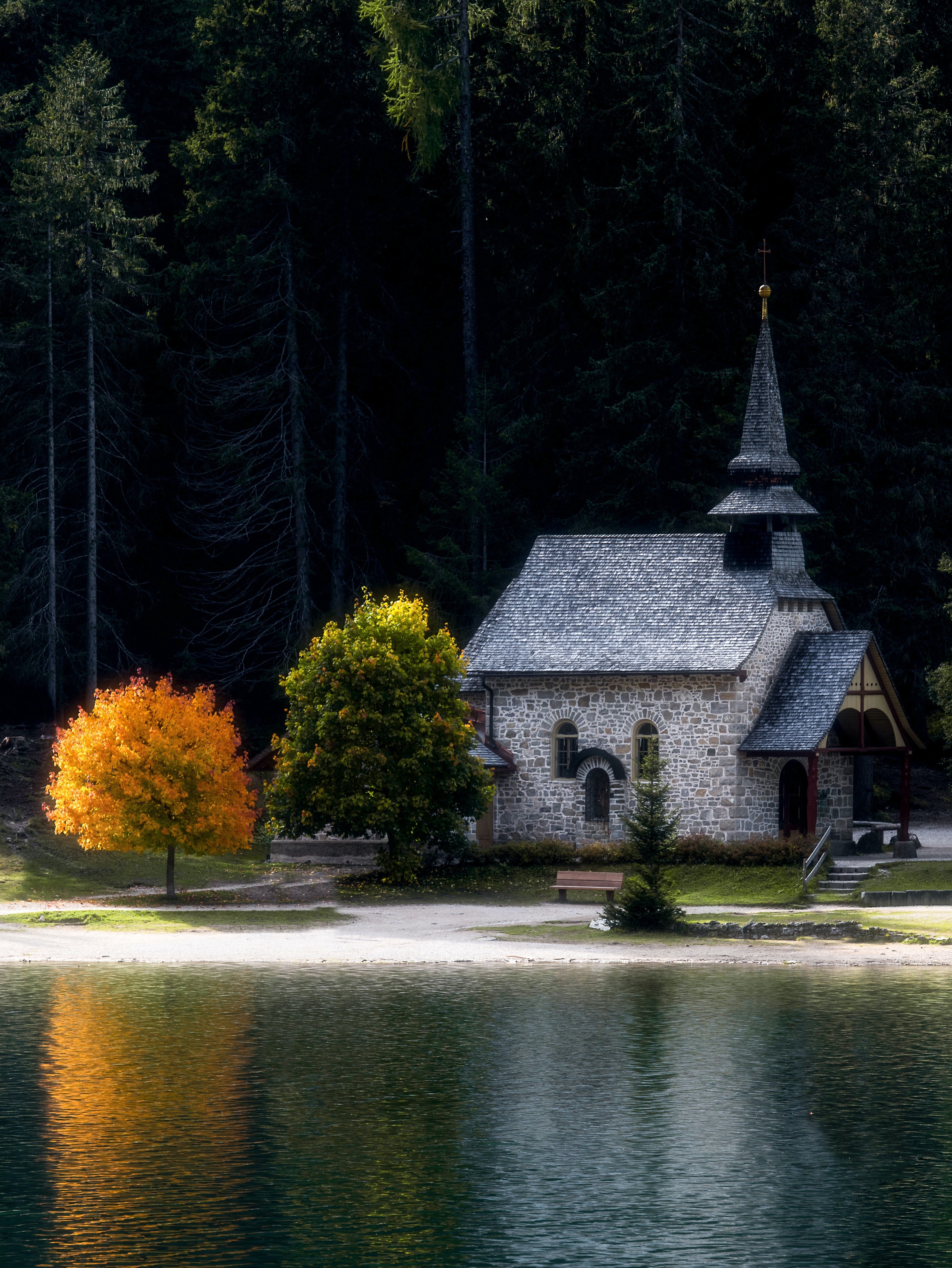 Eine kleine, malerische Kapelle liegt an einem ruhigen See und dichtem Wald.