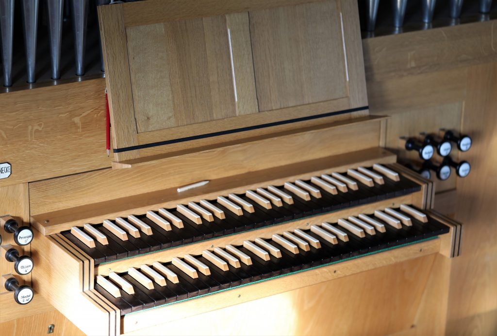 Nahaufnahme einer zweimanualigen hölzernen Orgelklaviatur und Registern.