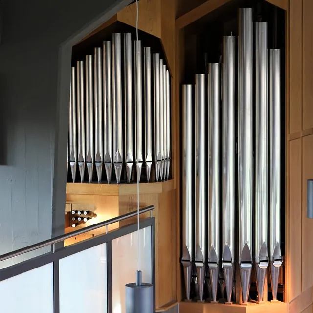 Moderne Kirchenorgel mit glänzenden Silberpfeifen und Holzgehäuse.