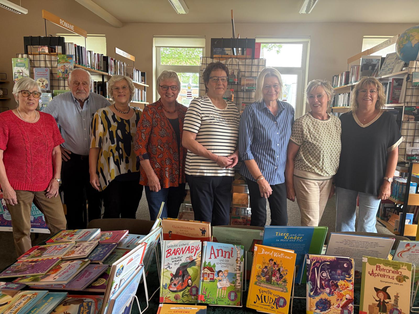 Gruppe von Erwachsenen und einem Kind mit Büchern in Bibliothek.