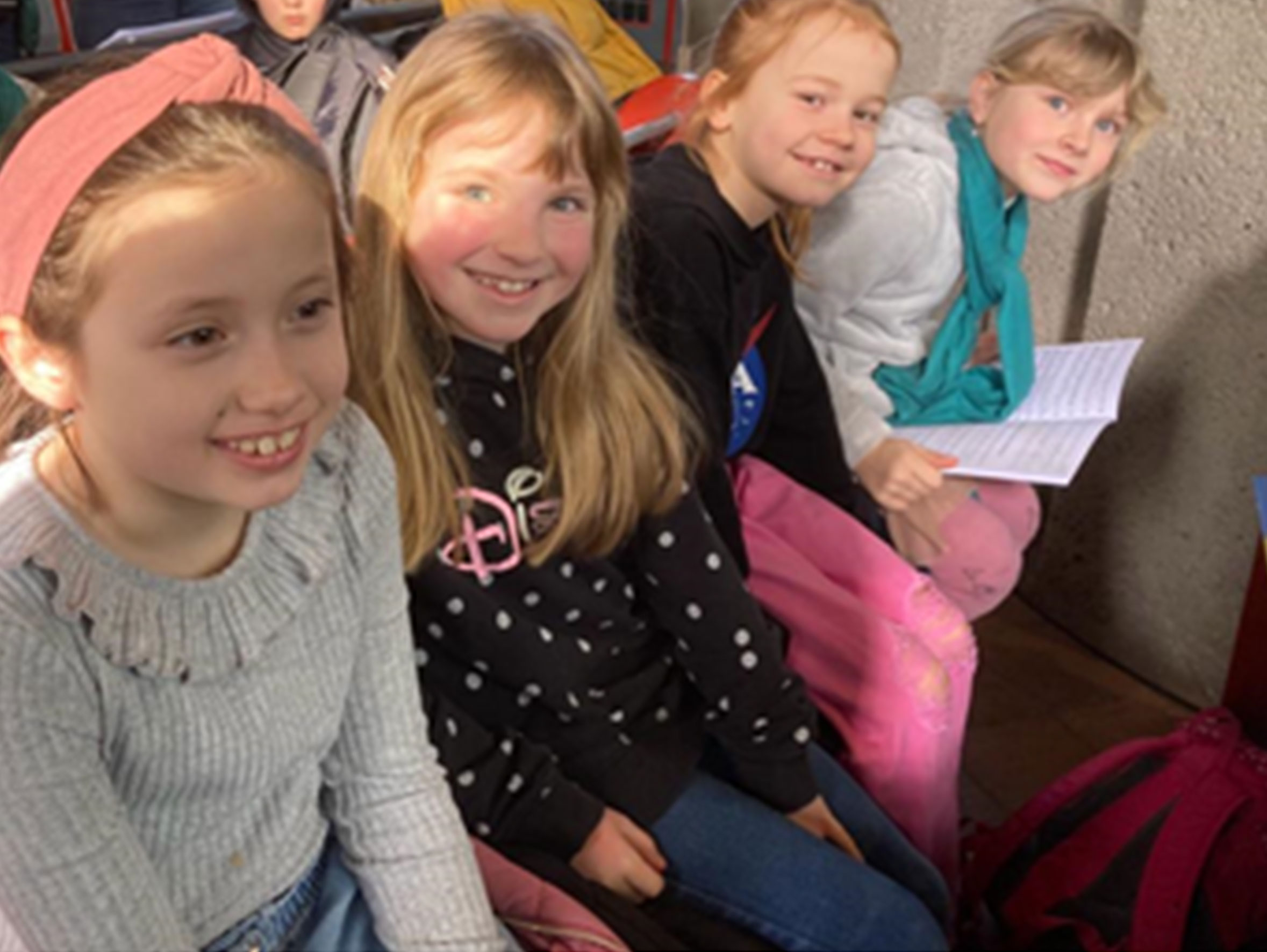 Vier lächelnde junge Mädchen sitzend, blicken in die Kamera.