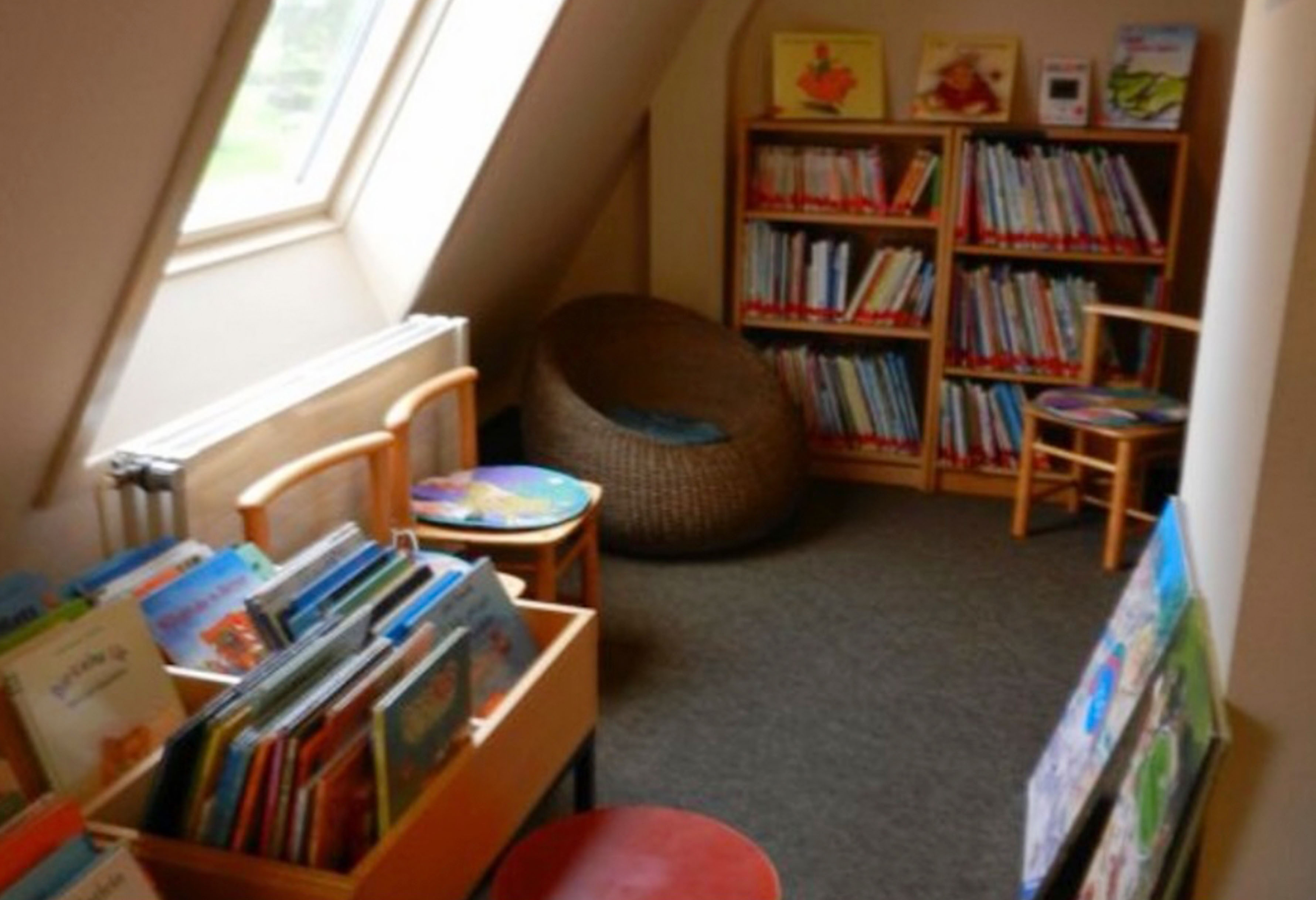 Gemütliche Kinderbibliotheksecke, Bücherregale, Lesesessel, natürliches Licht.