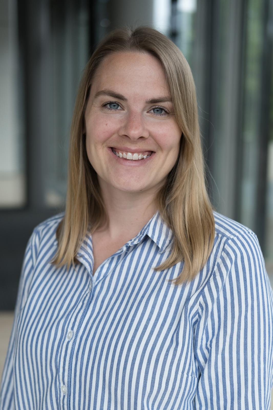 A friendly headshot of a smiling woman in a striped shirt.