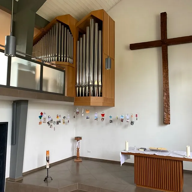 Modernes Kircheninterieur, großes Holzkreuz, Orgel, Altar, Kerzen.