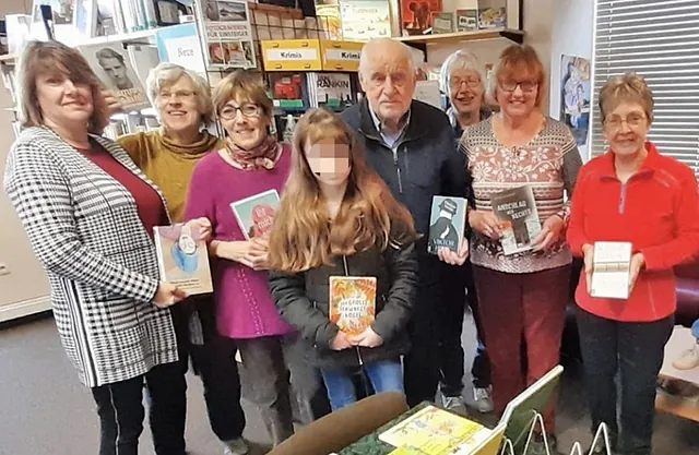 Gruppe von Erwachsenen und einem Kind mit Büchern in Bibliothek.
